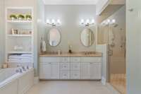 Spa like primary bath with double vanity, soaking tub, a large tiled shower, built in shelves for towels or products, marble countertops, as well as a private water closet.  Artisan tile flooring.
