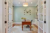 Private office with french doors and custom built in cabinets, shelves, and drawers