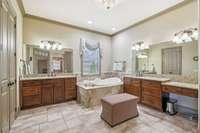 Primary spa bathroom with custom cabinetry, double vanities and private lavatory