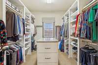 Spacious primary closet with custom shelving and drawers