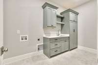 Luxury laundry room designed to make everyday tasks more enjoyable. Featuring custom cabinetry for ample storage, a built-in sink for added convenience, and quartz countertops for folding and organization.