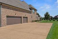 3 Car Side Entry Garage With Large Turnaround And Side Walk Leading To Back Patio