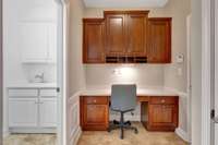 The mud room with desk and upper cabinets is next to the laundry room. The garage is to the right.
