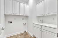 Laundry rom with wash sink and cabinets.