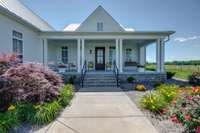 The porch’s timeless style and ample space make it both a functional extension of the home and a charming architectural highlight.