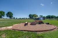The fire pit features a clean, geometric design surrounded by a bed of carefully laid gravel, adding texture and a natural touch to the gathering space. The gravel not only enhances drainage but also creates a rustic, earthy vibe.