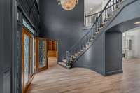 This two story foyer has stunning chandelier, freshly painted in Iron Ore for a modern, dramatic appearance, beautiful moldings, graceful curved staircase