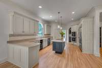 Kitchen features: Cabinets that have been recently and professionally painted, spacious island featuring a built in cooktop, brand new light fixtures, trash compactor
