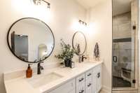 Double vanities with round mirrors and gorgeous, modern tiled shower + frameless glass