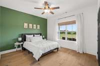 Bedroom #2 on the main floor has a beautiful green accent wall and hardwood flooring