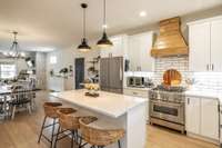Gorgeous, modern kitchen with island, Z-line range, wood hood vent.