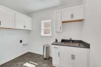 Large laundry room with cabinetry and sink included and access from the primary bathroom and the kitchen
Previously built home, features and selections may vary