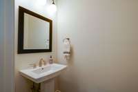 The powder room is located between the coat closet and the pantry.