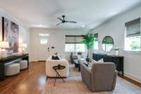 Modern open concept living space features hardwood floors, abundant natural light, and a ceiling fan for year-round comfort.