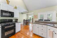 From the fridge looking back towards the gas oven, barstool seating, and dining room