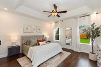 The primary suite is a peaceful retreat, featuring hardwood flooring, trey ceiling and fan.