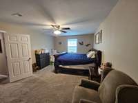 Primary bedroom has plenty of room for a sitting area and a ceiling fan.