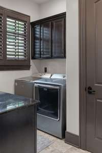 Main floor laundry with chute, sink, cabinets, and granite folding counter.