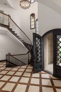 Heavy arched doors buffer the elements while the walnut inlay foyer warmly greats guests.
