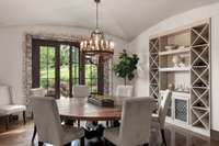 Formal dining with wine display opens to front porch. Note the exposed brick doorframe. Custom round table by designer Karmal Skillington made from reclaimed industrial Nashville flooring from early 1900’s. Seats 12 people.