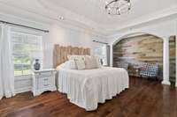 Large master bedroom with sitting area, lighted tray ceiling, and custom built-in