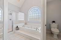 Master bath with 16-ft ceilings, large walk-in shower with two shower heads, body sprayers and large bench, jacuzzi tub, water closet, and heated tile floors