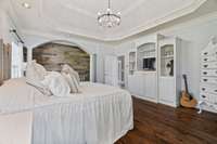 Large master bedroom with sitting area, lighted tray ceiling, and custom built-in