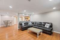 Living room in basement apartment. Kitchen is back off to the right. Door on the left is storage. Next door over leads back out to laundry room/mud room.