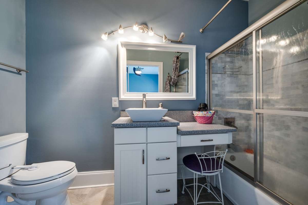 Bathroom with decorative basin, counters, and shower/tub with glass sliding doors.