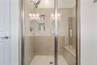 Large tiled shower with a bench and inset shelves.  The light above is also an exhaust fan.