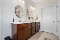 Primary ensuite bathroom with double vanity sinks, artisan tile flooring, a walk in tile shower, a soaking tub, linen closet, AND a water closet for privacy.