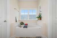Soaking tub just below the window providing natural light but also privacy.  Built in shelves and a ledge on either side for accessories or toiletries