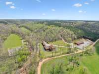 Overview of the front of the property showing Main lodge in middle, bunk house/garage to the right and dog kennels to the far right. The venue is located just to the left of the main lodge on the creek. The driving range is located in left green area