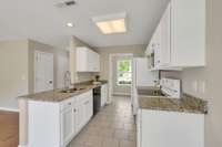 The kitchen boasts granite counters, white cabinets, and a tile floor.