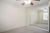 The front bedroom's mirrored wall reflects light from the large window.