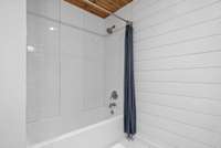 Downstairs bathroom with tub/shower combo with tile walls.