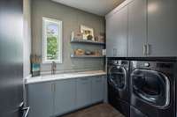 Main laundry on the first floor includes two dry away racks and marble countertops.