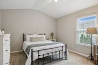 Spacious primary suite with vaulted ceiling, neutral palette, and abundant natural light offers a peaceful place to unwind.