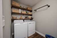 Roomy laundry room with shelves and a drying bar, just next to the garage door for your convenience.