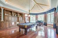 The billiard room is large and welcoming with a beautiful wood ceiling. Built-in shelving lines the side wall and the large bay windows offer views of the Arnold Palmer golf course.