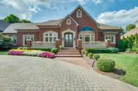 Gracious entry with paver driveway and brick walkway lead to the front terrace and double doored entry.