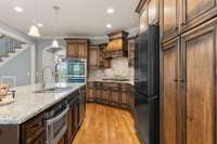 The kitchen features a gas cooktop, tile backsplash, maple cabinets, a counter depth refrigerator, a microwave drawer and double ovens.
