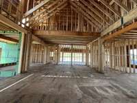 Great room with two-story vaulted ceiling with view of the kitchen *this house is under construction. Photo taken 6/22/25