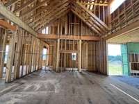 Great room with two-story vaulted ceiling with ample light! *this house is under construction. Photo taken 6/22/25