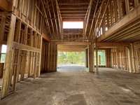 Great room with two-story vaulted ceiling with ample light! *this house is under construction. Photo taken 6/22/25