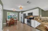 Spacious eat-in Kitchen with white cabinetry, granite countertops, newer tile backsplash,  stainless steel appliances and pantry.