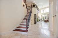 View from the entry highlighting the soaring ceilings, the wrought iron details, and the entry to the wine alcove.