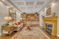 Coffered ceilings, custom bookcases, and a lovely gas fireplace elevate this elegant living room.