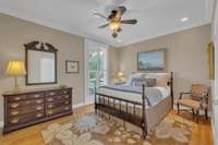 A secondary bedroom suite provides a restful retreat with neutral paint, hardwood floors, and  plantation shutters.