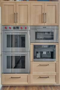 A dream lineup for any chef—Wolf double ovens, Miele coffee and espresso system, and microwave—all built into custom oak cabinetry for beauty and function.